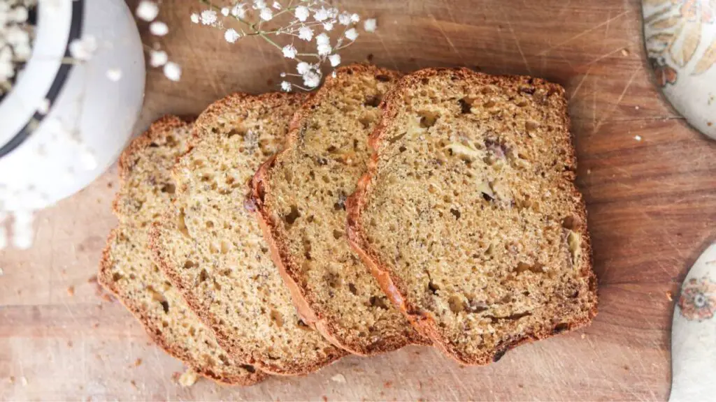 A sliced loaf of einkorn sourdough banana bread on a wooden cutting board. 