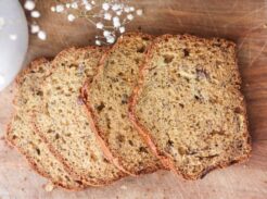 A sliced loaf of einkorn sourdough banana bread on a wooden cutting board.