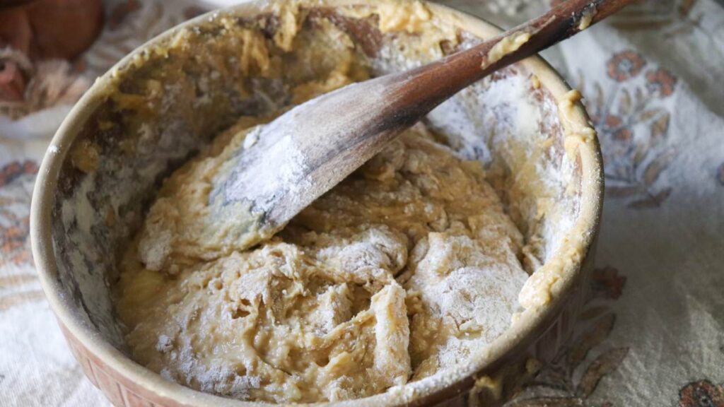 A bowl of banana bread batter with a wooden spoon in it. 