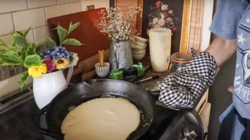 Cooking sourdough crepes in a cast iron skillet.