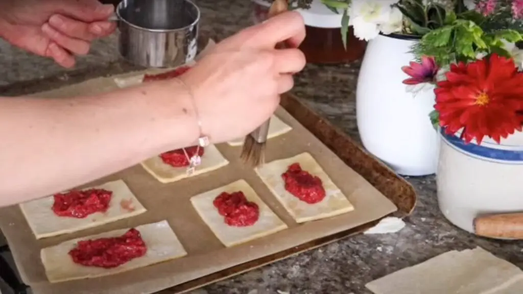 Filling homemade pop tart dough squares with homemade raspberry jam.