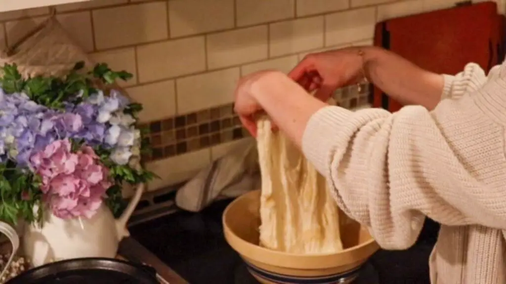 Performing stretch and folds on a ball of bread dough.