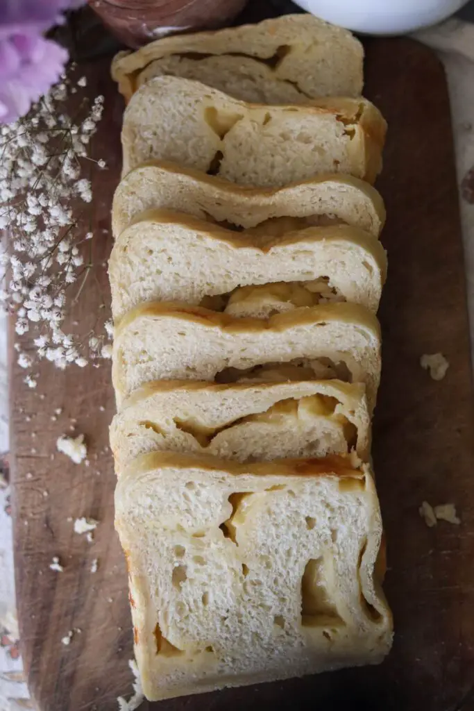 Slices of cheese sourdough bread on a wooden counter.