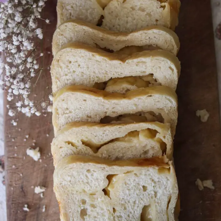 Slices of cheese sourdough bread on a wooden counter.