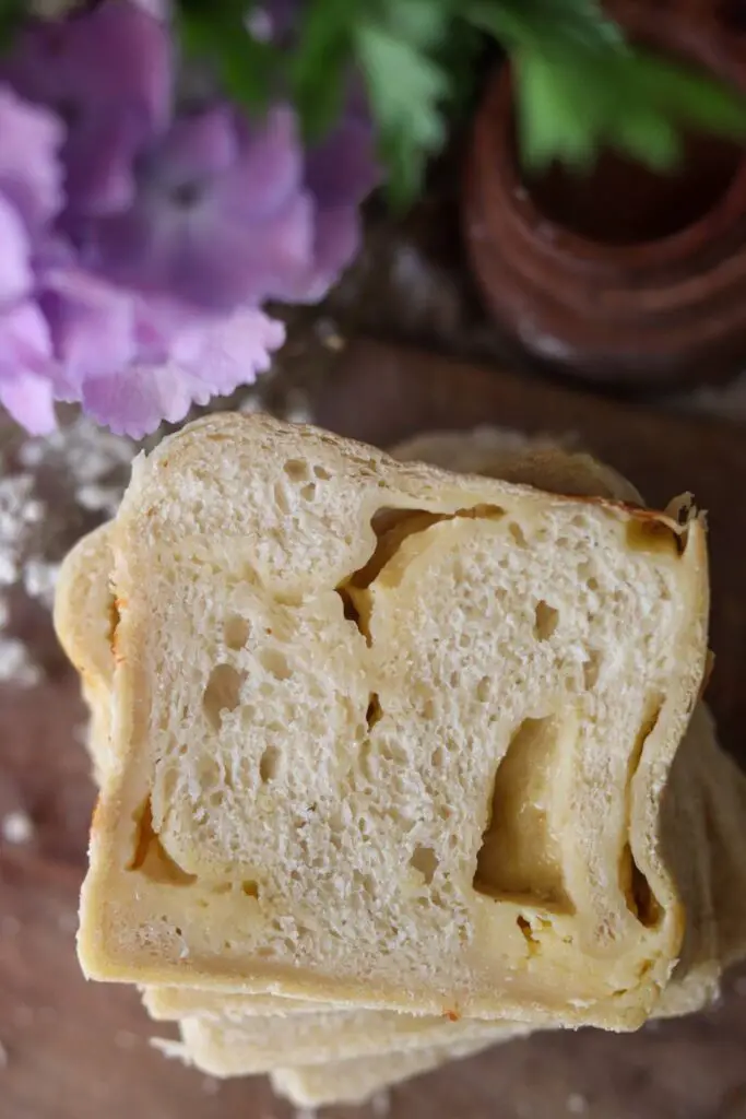 A slice of cheese sourdough bread on a wooden counter.