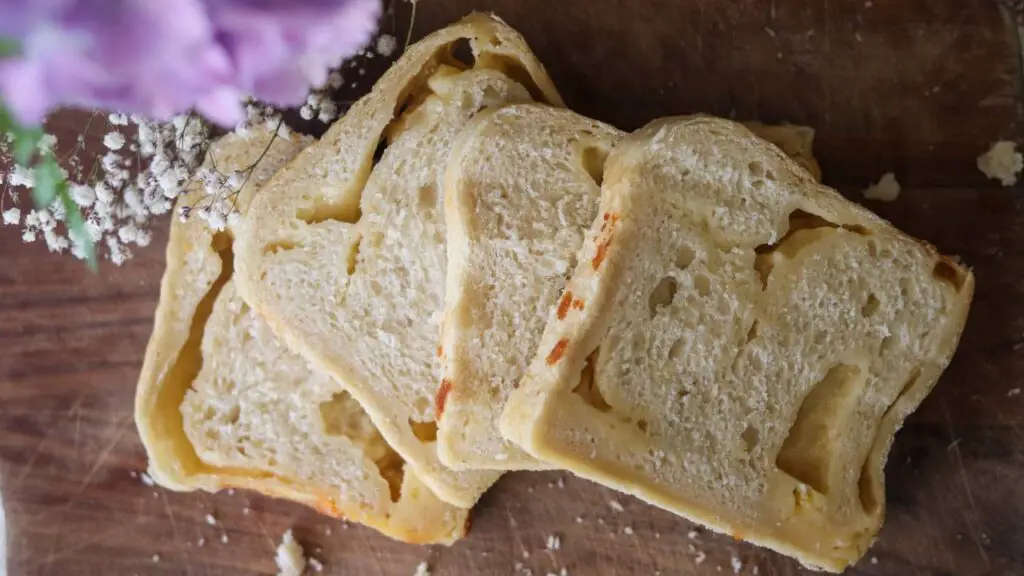 Sliced sourdough cheese bread on a wooden counter.