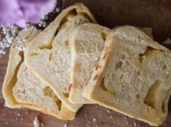 Sliced sourdough cheese bread on a wooden counter.