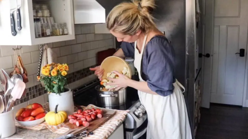 Adding chopped vegetables to a pot on the stove.