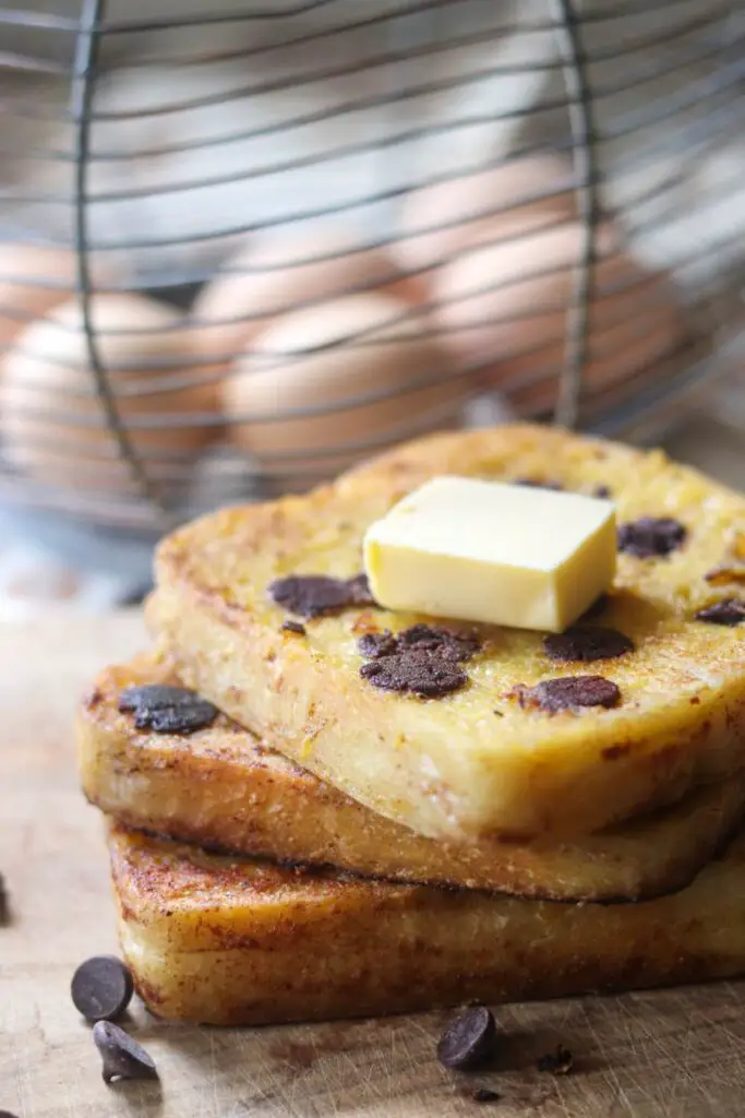 Sourdough french toast with butter on top and eggs in the background.