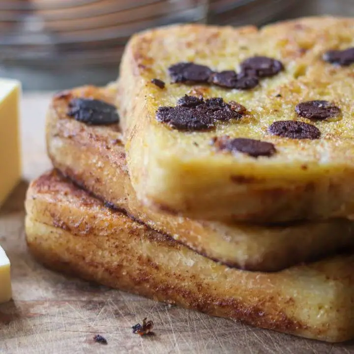 Sourdough french toast with chocolate chips on top and butter next to it.