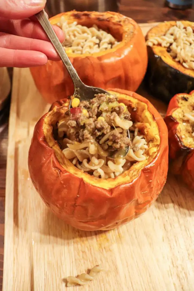 Scooping beef soup out of a cooking pumpkin bowl.