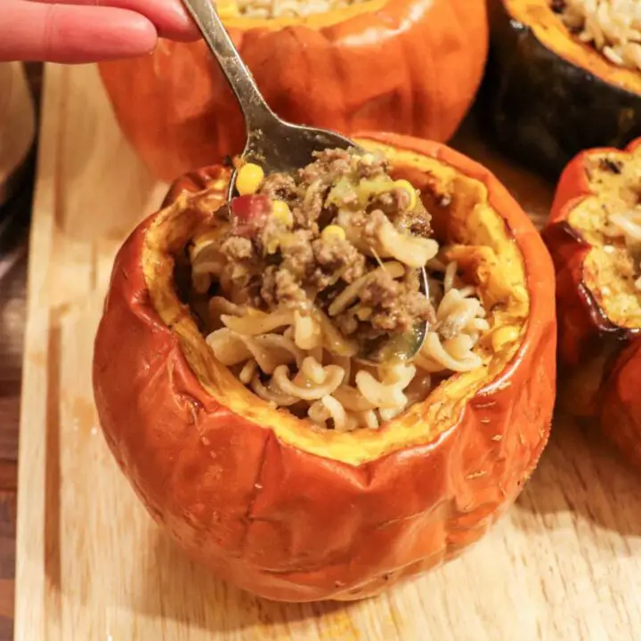 Scooping beef soup out of a cooking pumpkin bowl.