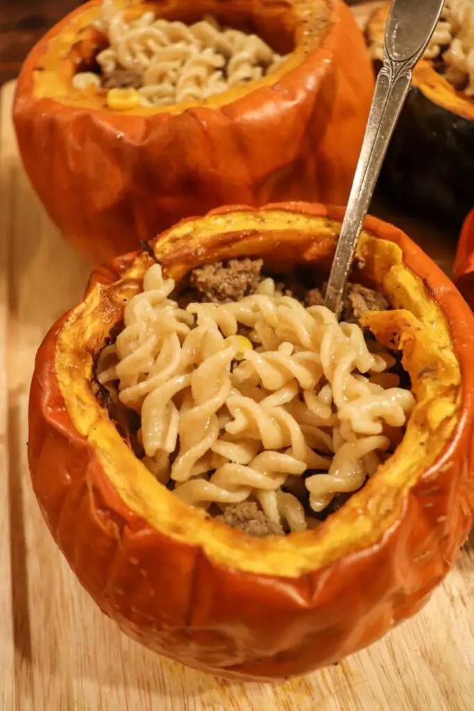 A pumpkin filled with beef and noodles with a spoon in it.