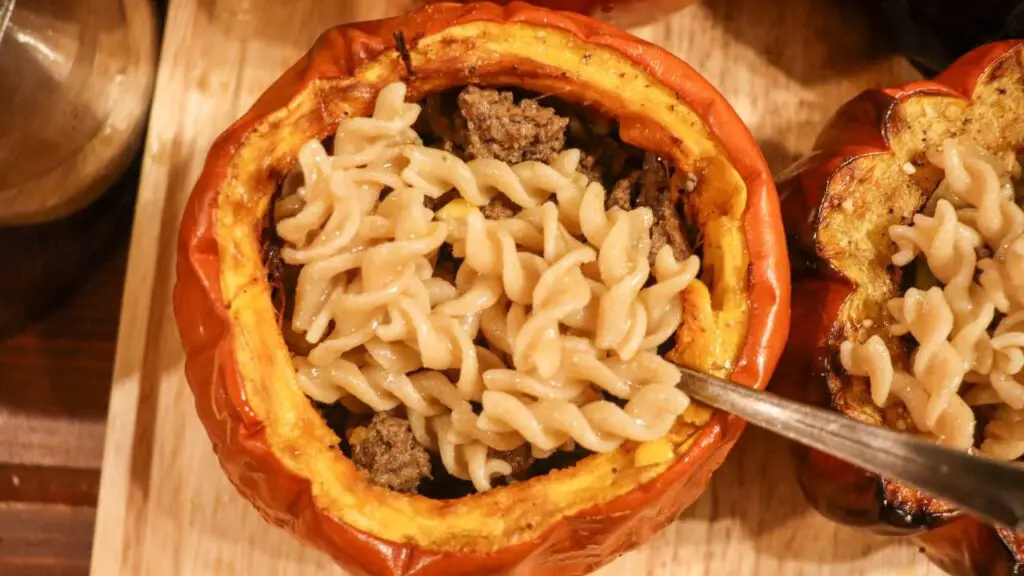 Looking down on a cooked pumpkin filled with beef soup and noodles.