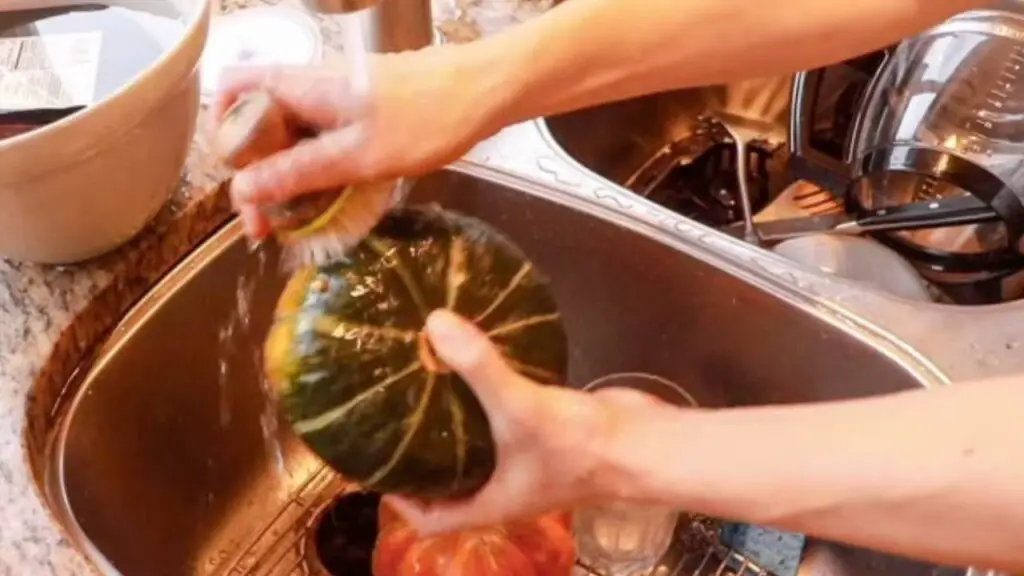 Washing a pumpkin in the sink.