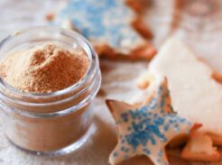 A jar of meringue powder with homemade frosted sugar cookies.