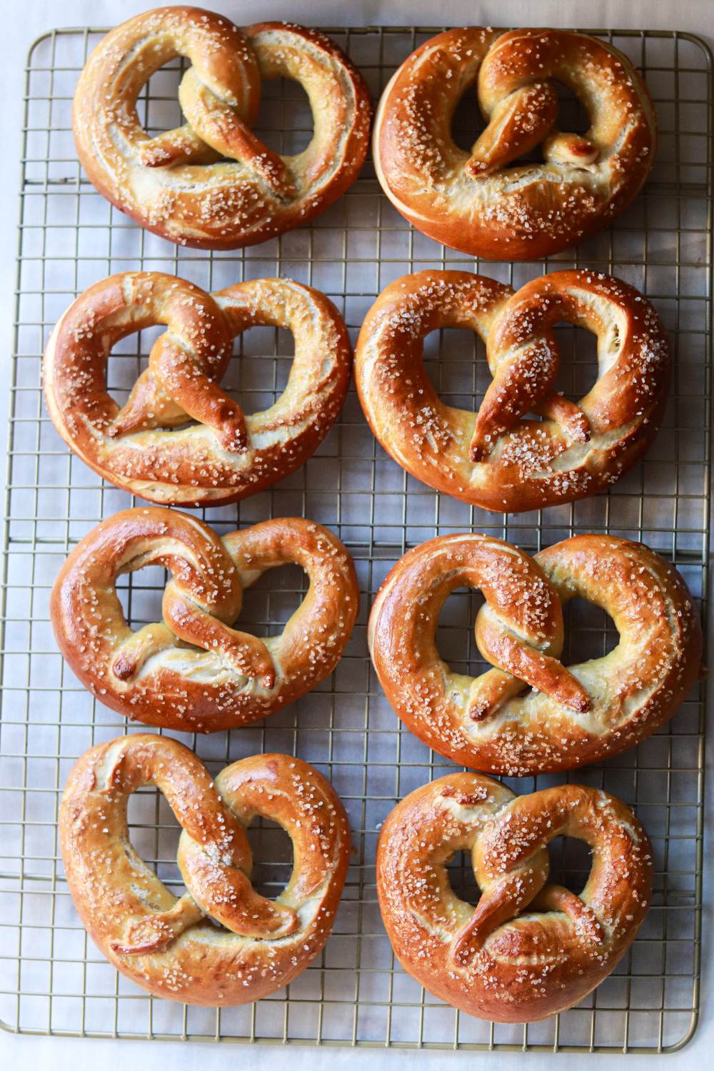Eight soft pretzels on a cooling rack.