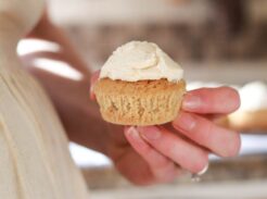 Holding a frosted vanilla cupcake.