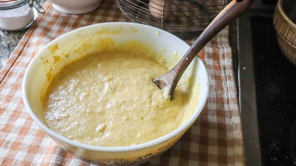Cornbread batter in a bowl with a wooden spoon.