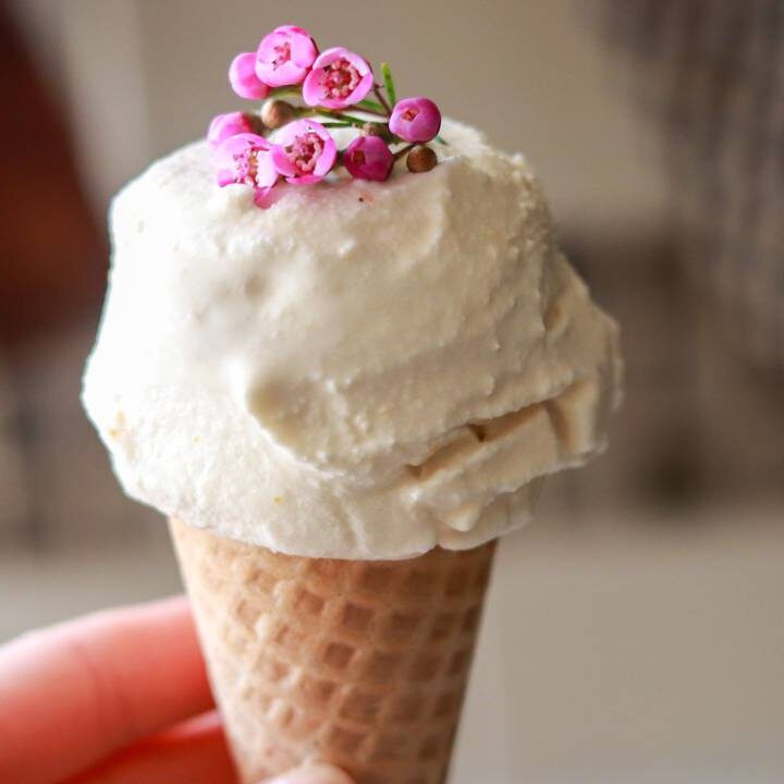 Holding an ice cream cone with vanilla ice cream and pink flowers.