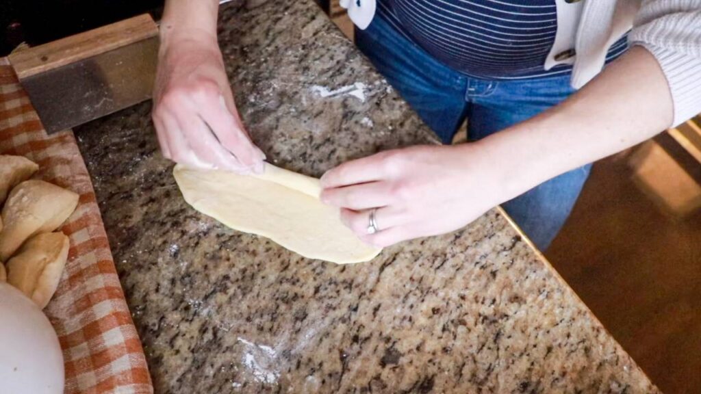Rolling dough into hot dog buns.