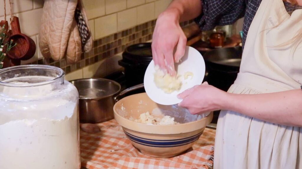 Adding dough paste to a bowl of hot dog bun dough.