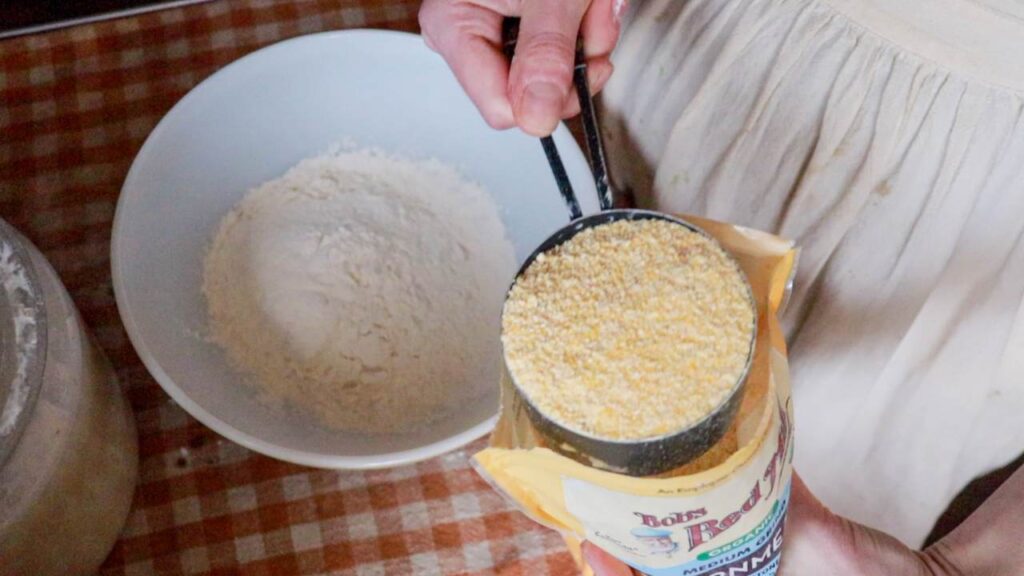 Measuring cornmeal into a mixing bowl.