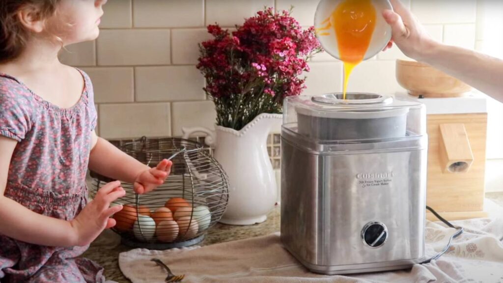 Child watching as egg yolks are poured into an ice cream maker.