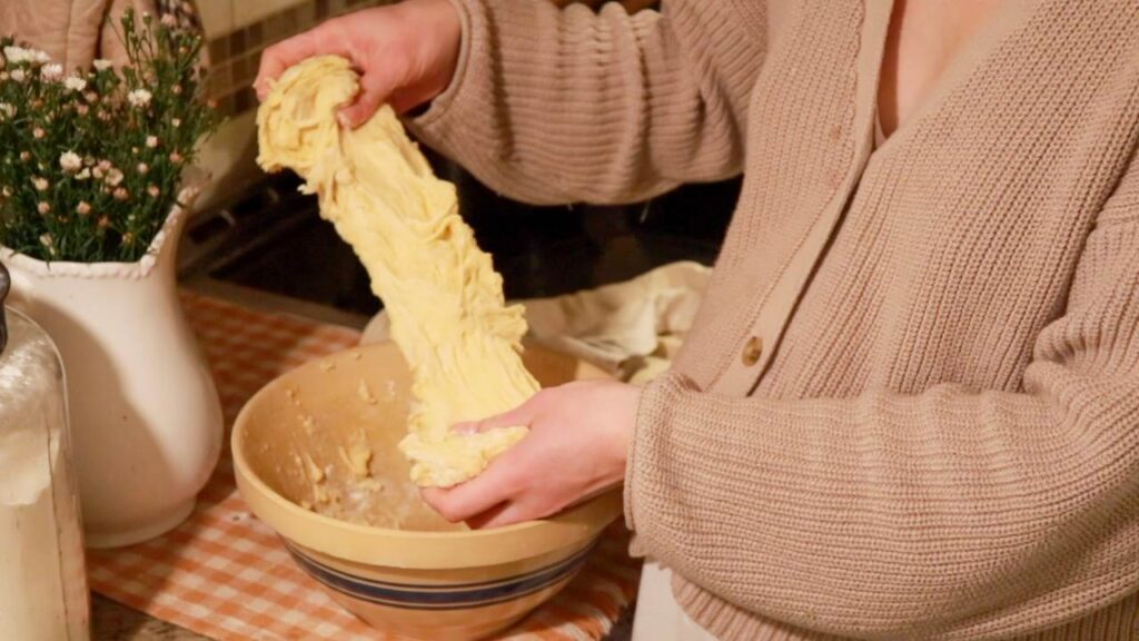 Stretching and folding hot dog bun dough.