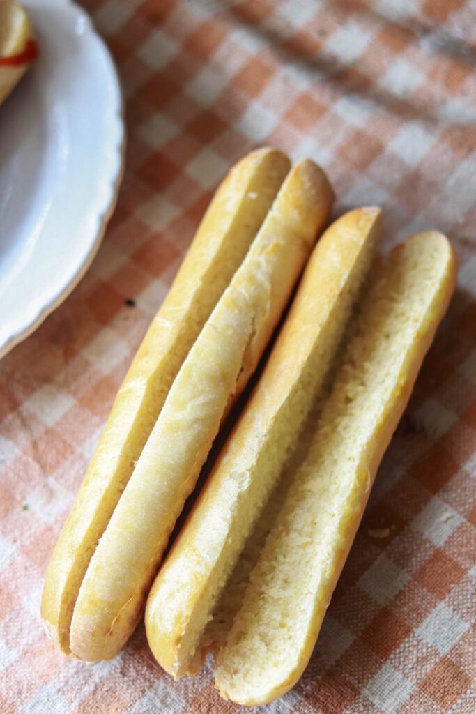 Two hot dog buns sliced on a checkered table.