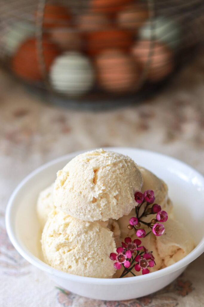 A bowl of homemade vanilla ice cream with pink flowers inside.