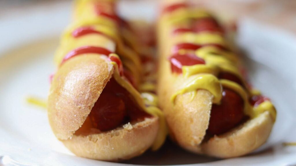 Two hot dogs on homemade buns with mustard and ketchup.