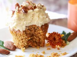 a carrot cake cupcake sitting on a small plate with a bite taken out.