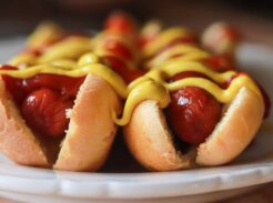 Two hot dogs sitting on a plate with mustard and ketchup.