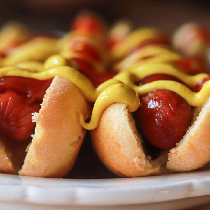 Two hot dogs sitting on a plate with mustard and ketchup.