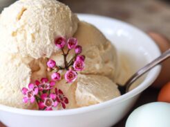 A bowl of homemade vanilla ice cream with fresh eggs next to it.