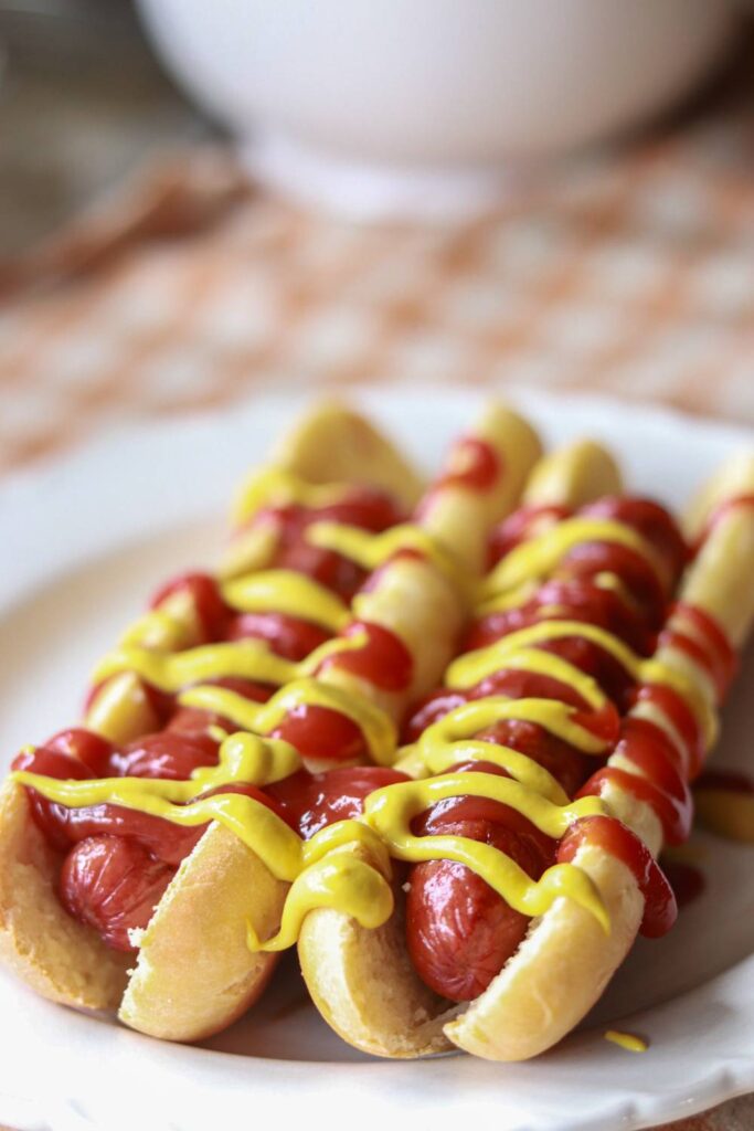 A plate with two hot dogs with mustard and ketchup.