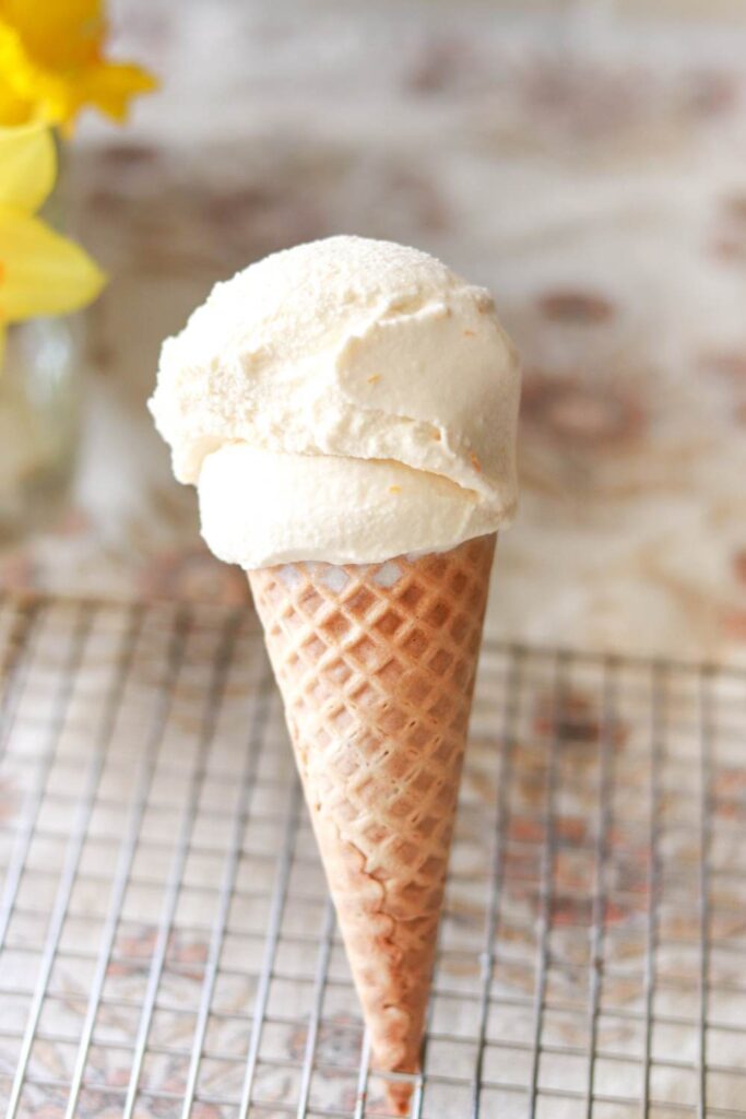 A vanilla ice cream cone standing up in a baking rack.