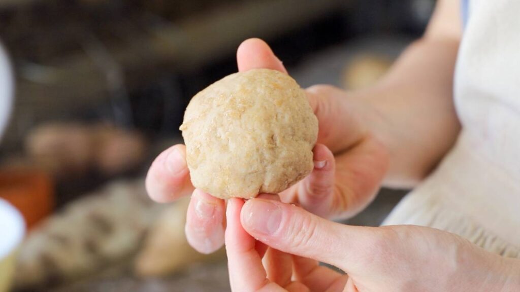 Hands holding a ball of sourdough dough