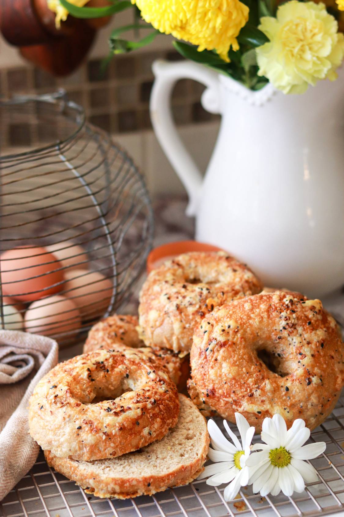 closeup of homemade freshly milled sourdough bagels cut in half with everything bagel seasoning sprinkled on top.