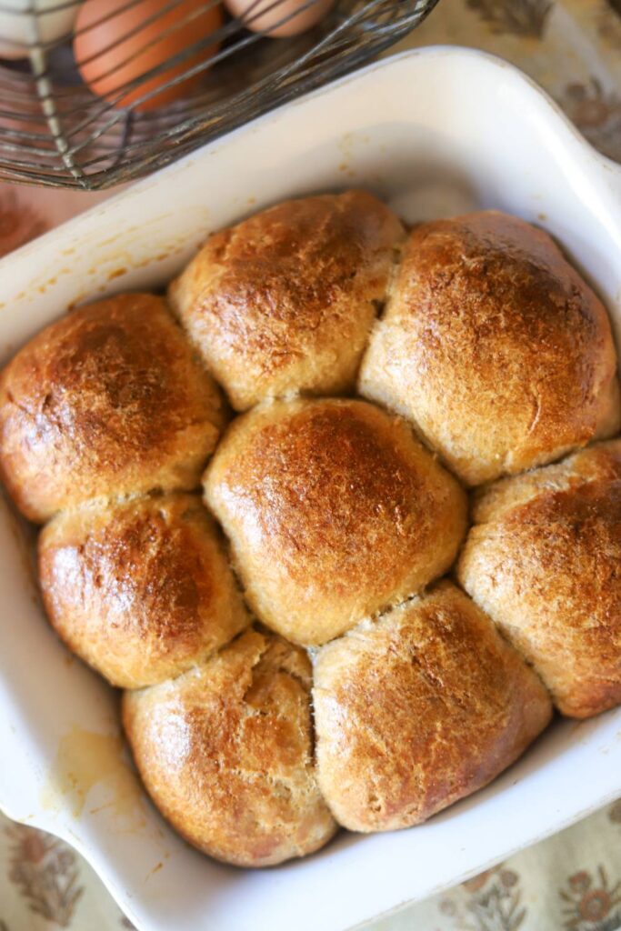 Top view of golden brown sourdough rolls in a white baking dish