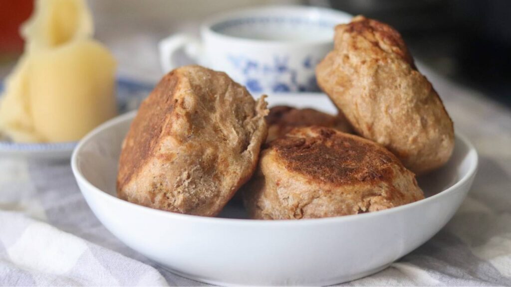 Whole wheat sourdough English muffins served in a white bowl.