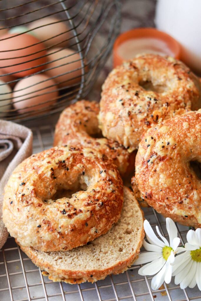 closeup of homemade freshly milled sourdough bagels cut in half with everything bagel seasoning sprinkled on top.