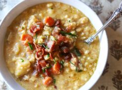 Bowl of creamy corn chowder topped with crispy bacon and chopped chives.