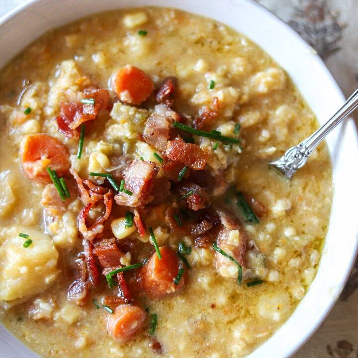 Bowl of creamy corn chowder topped with crispy bacon and chopped chives.