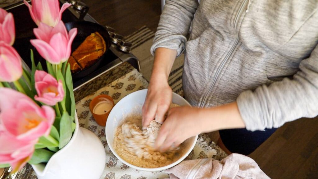 Hands mixing sourdough dough in a large bowl