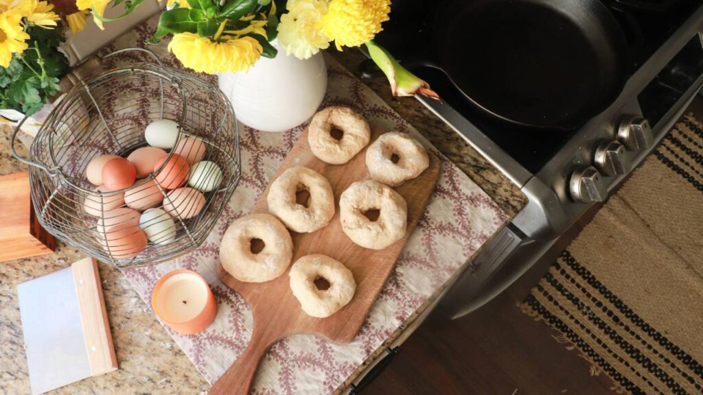 raw sourdough bagel dough rolled into donut shapes on a wooden cutting board