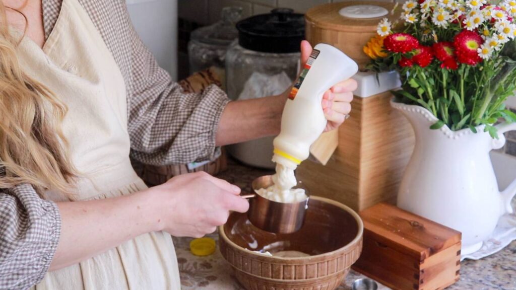 a woman measuring out buttermilk to put into the pancake mix bowl.