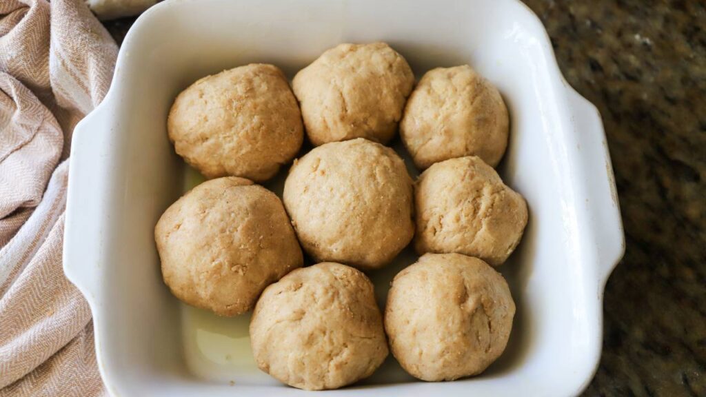 Unbaked sourdough rolls in a white baking dish