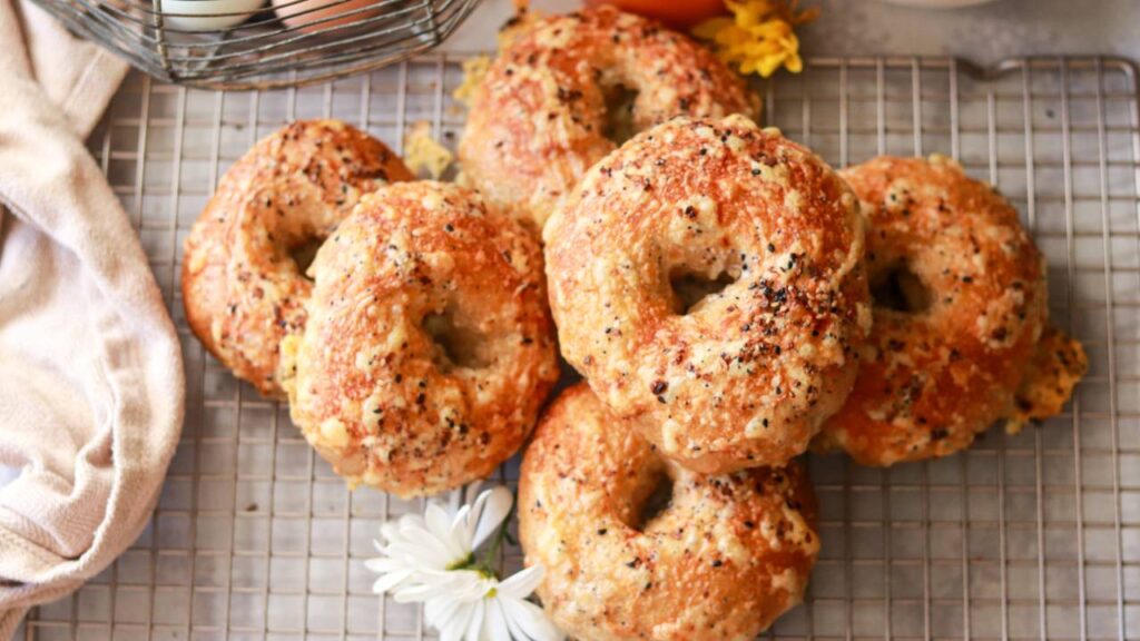 closeup of a stack of homemade freshly milled sourdough bagels with everything bagel seasoning sprinkled on top.